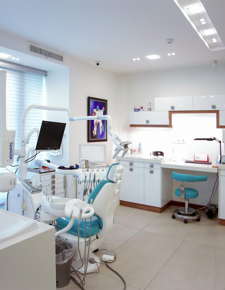 Interior de un consultorio dental con sillón, lámpara e instrumental ordenado
